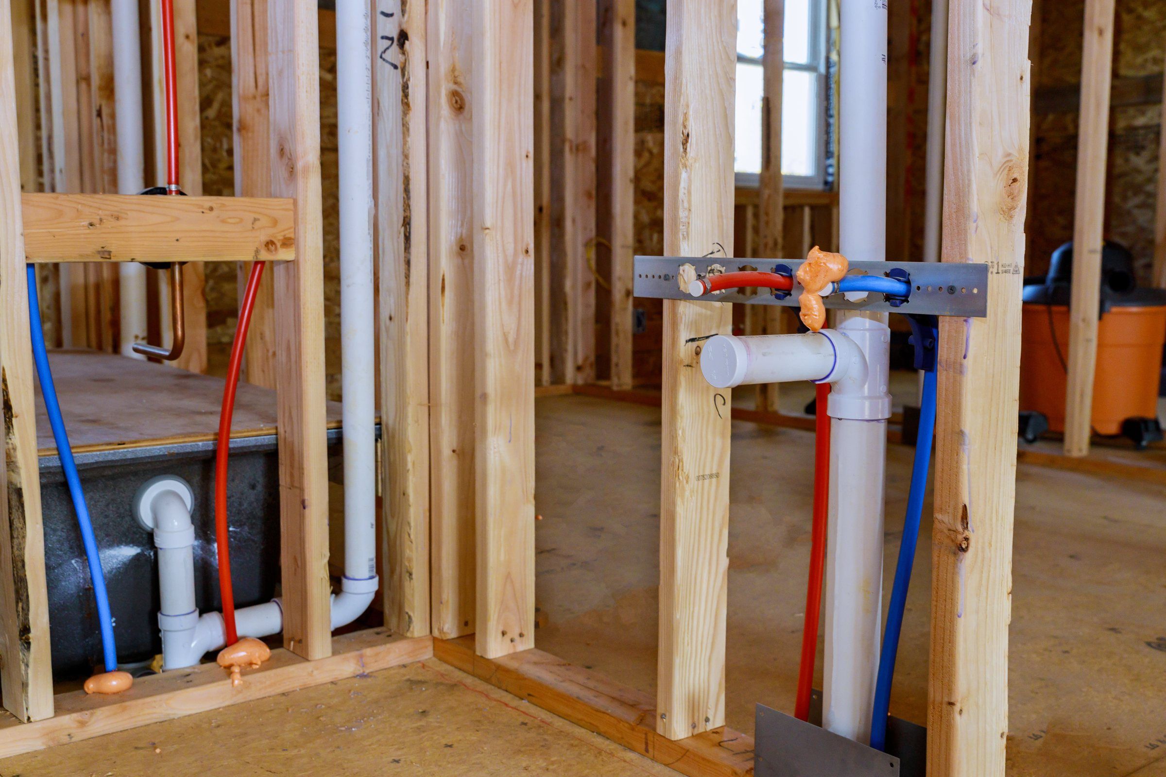Plumbing rough-in in a framed house: PEX manifold, copper stub-outs and PVC drain lines