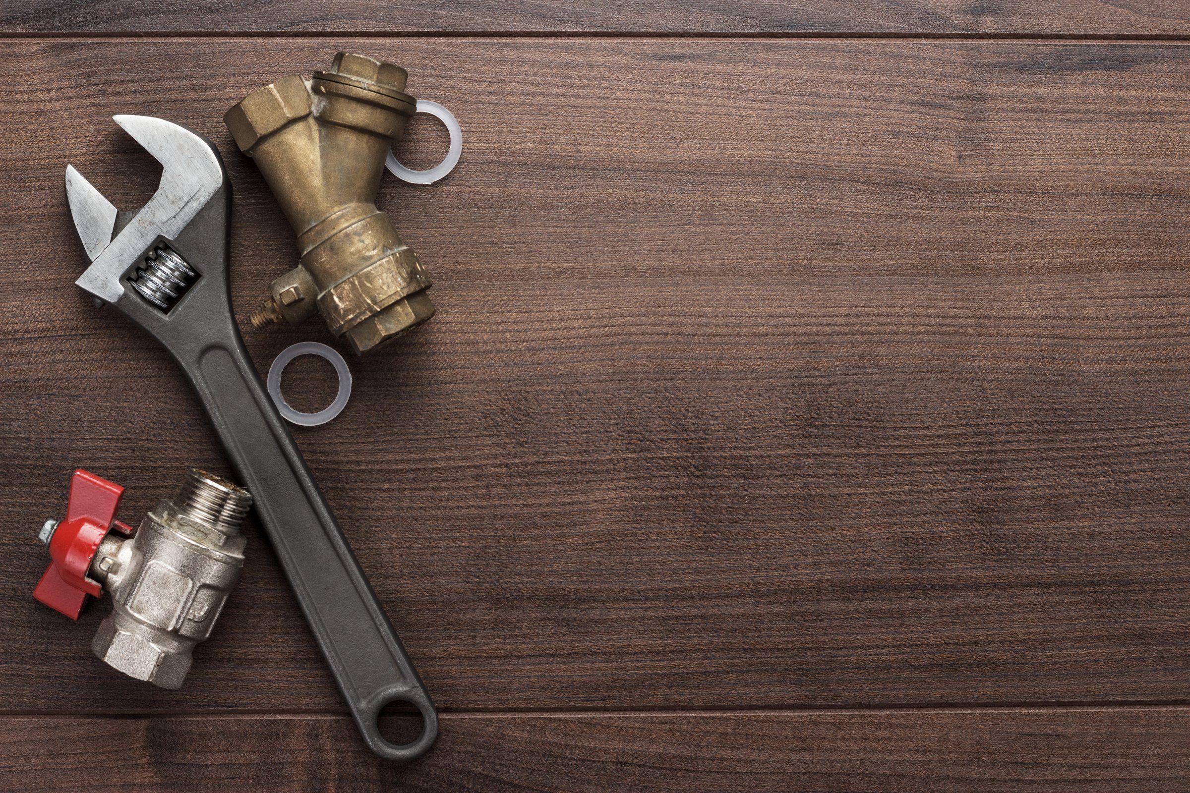 Pipe wrench and brass plumbing valves on a wooden workbench